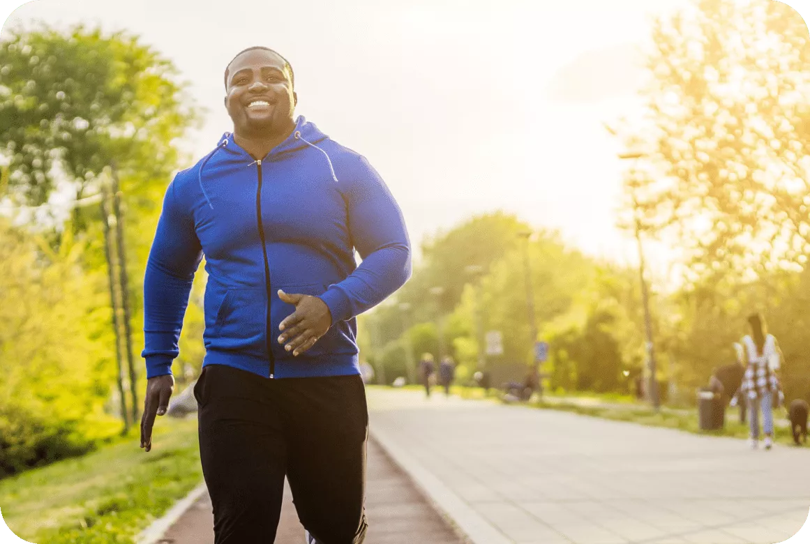 A dark-skinned man running on the street during the afternoon