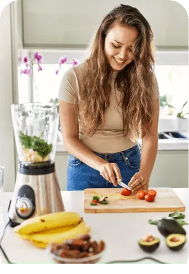 A smiling woman cutting tomatoes on a cutting board in the kitchen