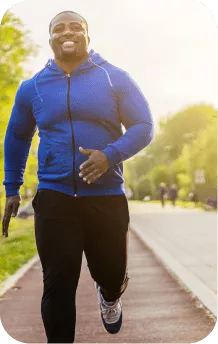 A dark-skinned man running on the street during the afternoon
